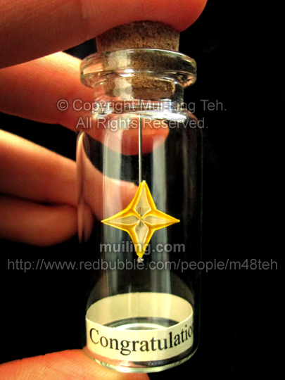 Miniature yellow origami star in a bottle by Mui-Ling Teh, with the message 'Congratulations!' written below on a yellow label