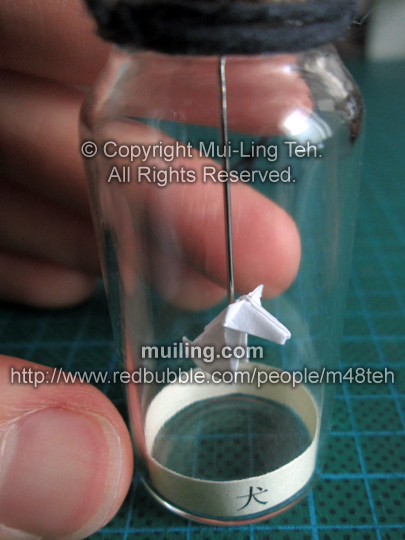 Cute white miniature origami dog in a bottle from the Shengxiao Chinese circle of animals zodiac