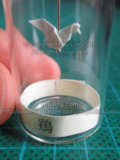 Cute white miniature origami rooster in a bottle from the Shengxiao Chinese circle of animals zodiac