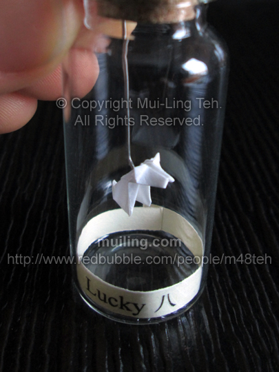 cute miniature origami dog in a bottle, with the label "Lucky 8"