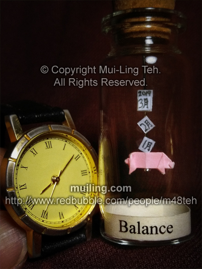 Miniature origami pig and calendar in a bottle with the label 'Balance'