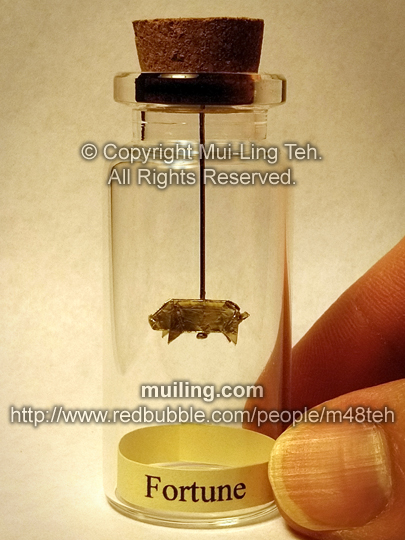 Miniature origami gold pig of in a small bottle, with the label Fortune
