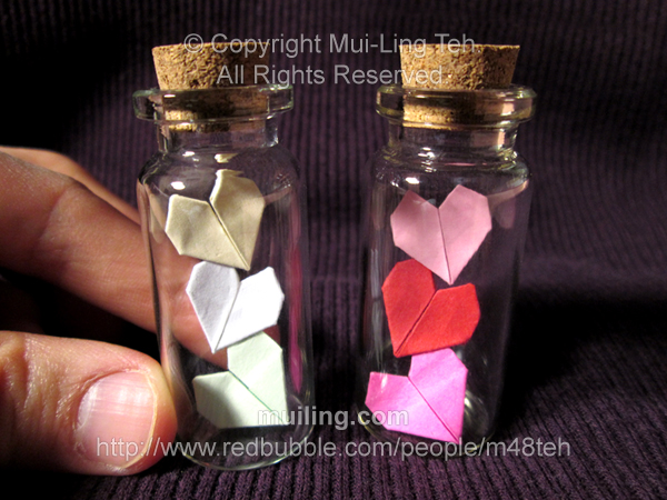 Three cascading miniature origami hearts in small bottles by Mui-Ling Teh