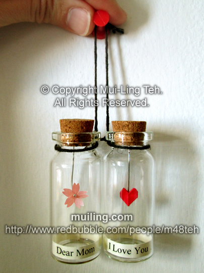 Miniature origami cherry blossom and red heart in bottles with labels "Dear Mom" and "I Love You"
